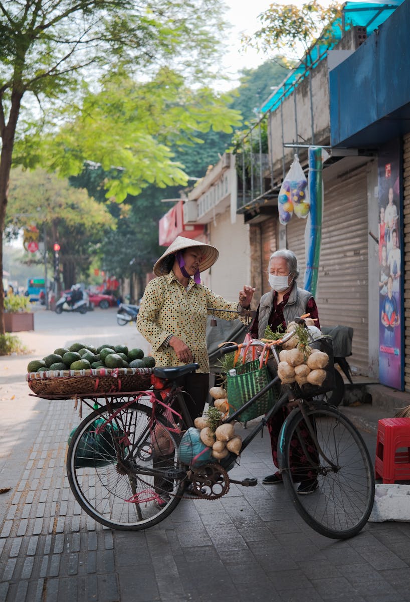 Women Standing with a Bike with Vegetables